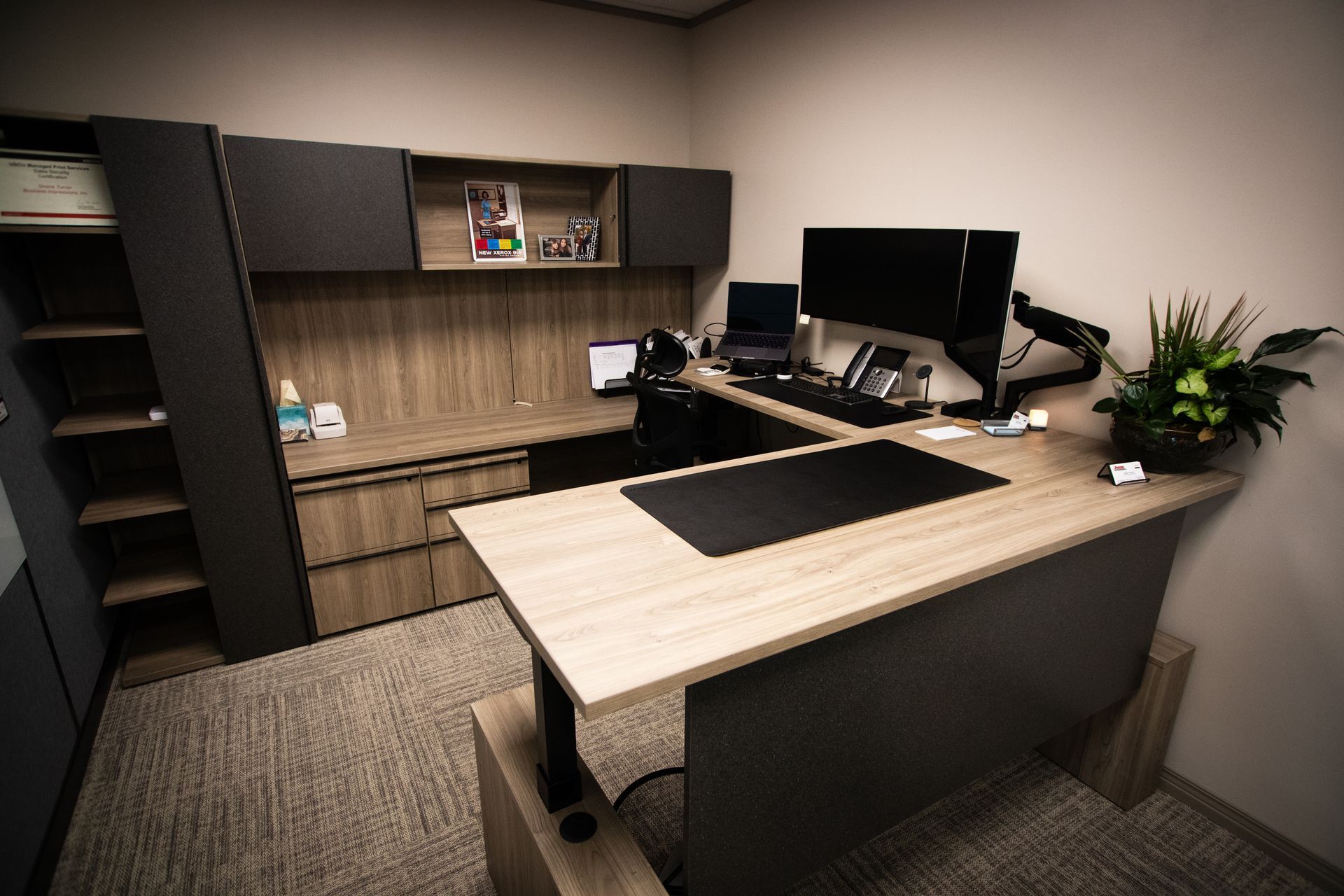 There is a desk with two monitors on it in the office.