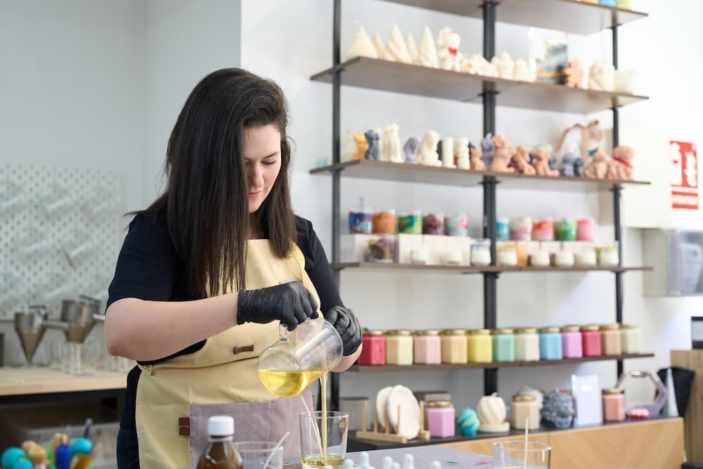 Woman crafting products with retail shelving displaying finished goods, relevant to commercial stora