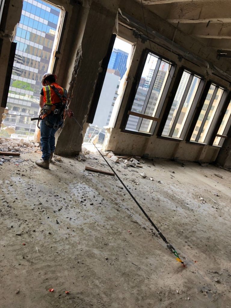 Worker in a high-rise construction site with debris, concrete columns, and large window openings.