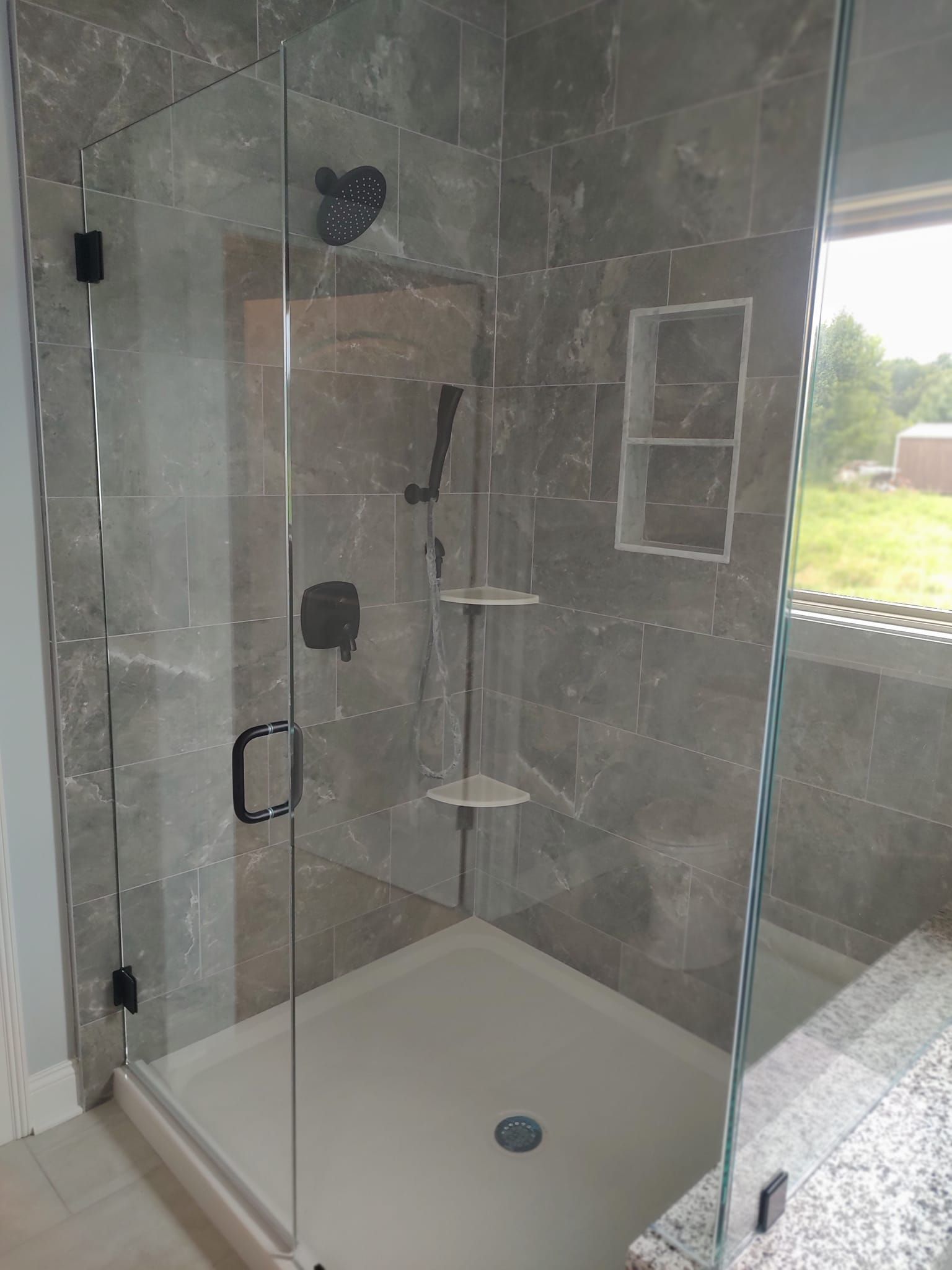 Bathroom vanity with a gray cabinet, white countertop, black fixtures, and a large mirror.