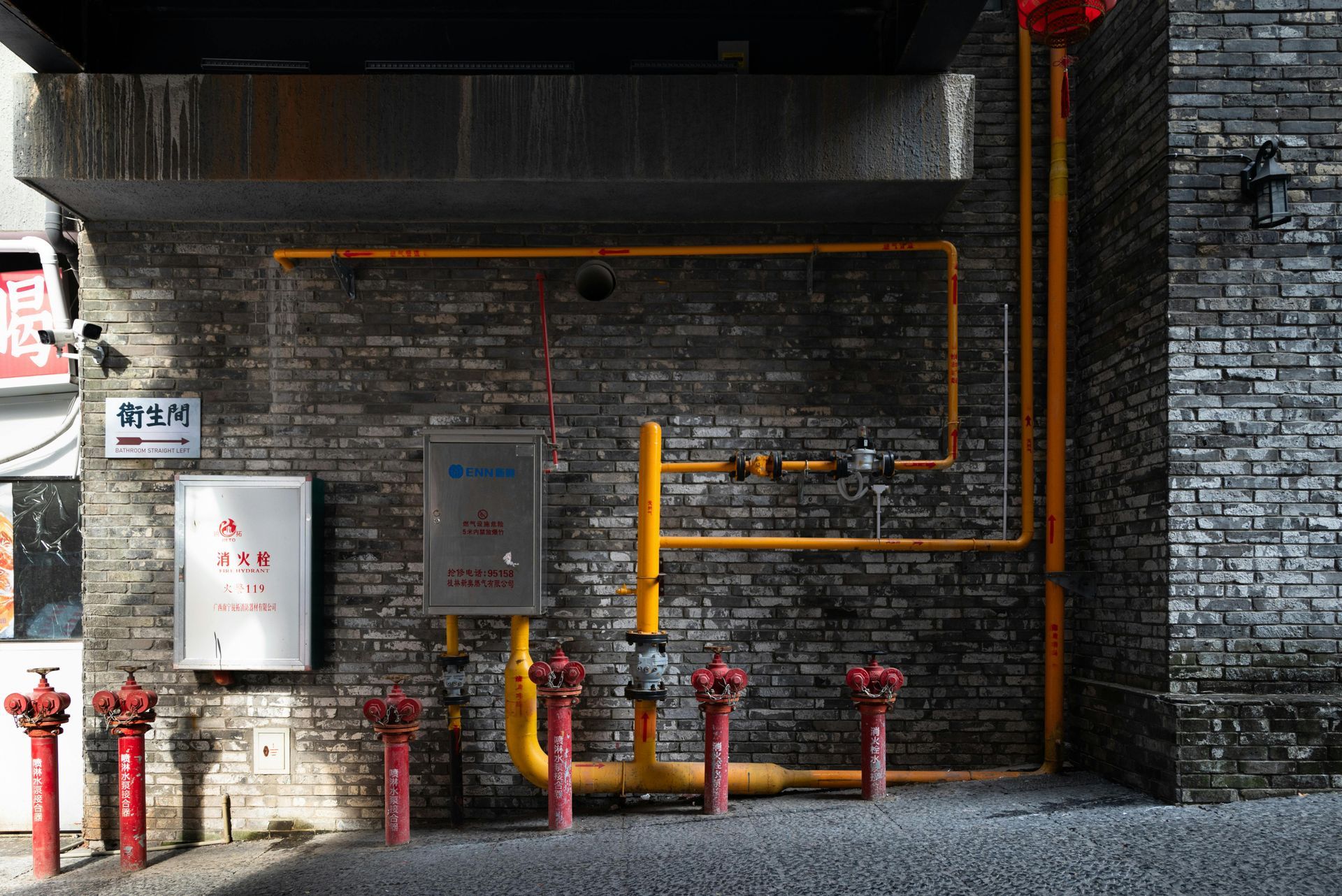 Water hookup box with red and blue pipes, gold valves, white box, and vent pipe. Mounted between wooden beams.