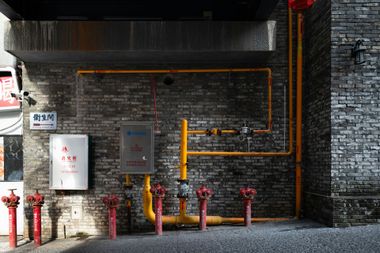 Water hookup box with red and blue pipes, gold valves, white box, and vent pipe. Mounted between wooden beams.