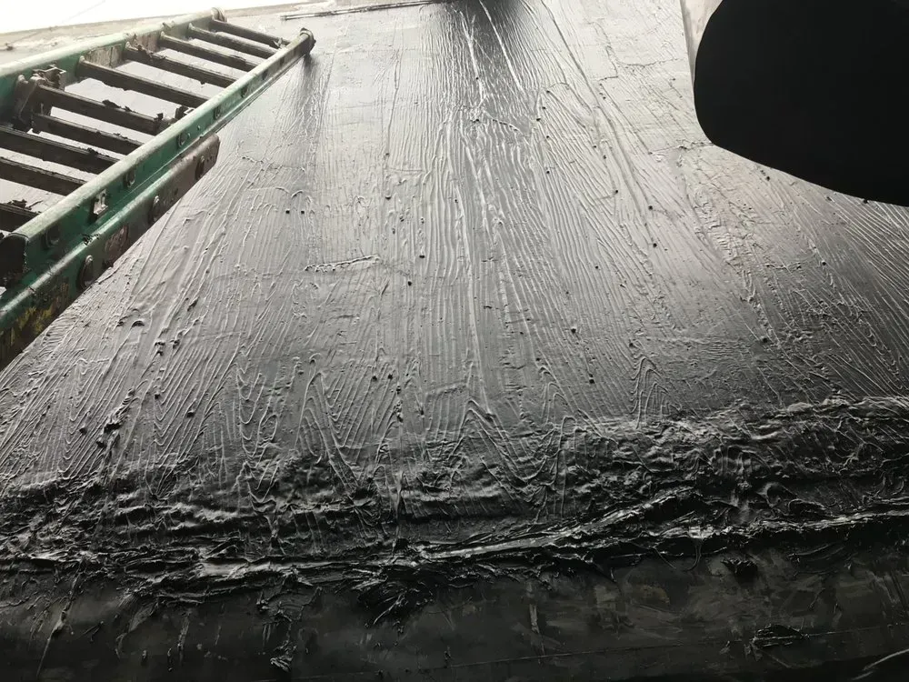 Black tar roof with a ladder leaning against it.
