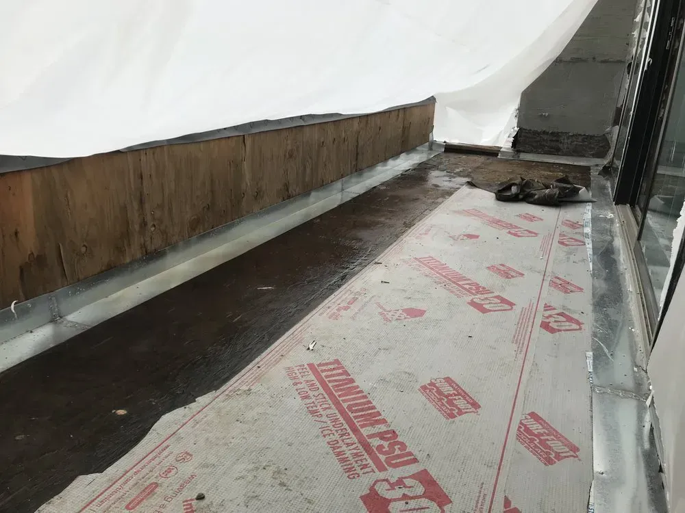 Construction site with a wooden barrier, waterproof underlayment, and a white covering.