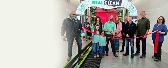 Group cutting a red ribbon at the Real Clean storefront entrance