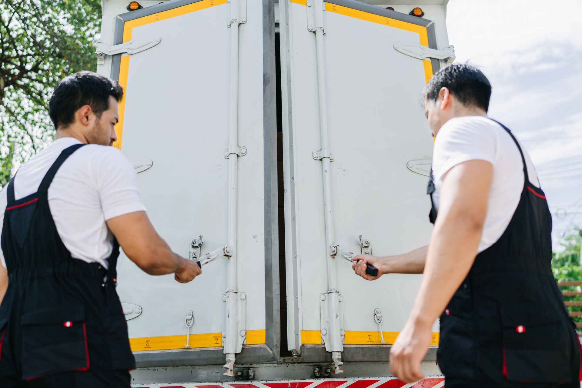 Professional movers opening truck doors for relocation service.