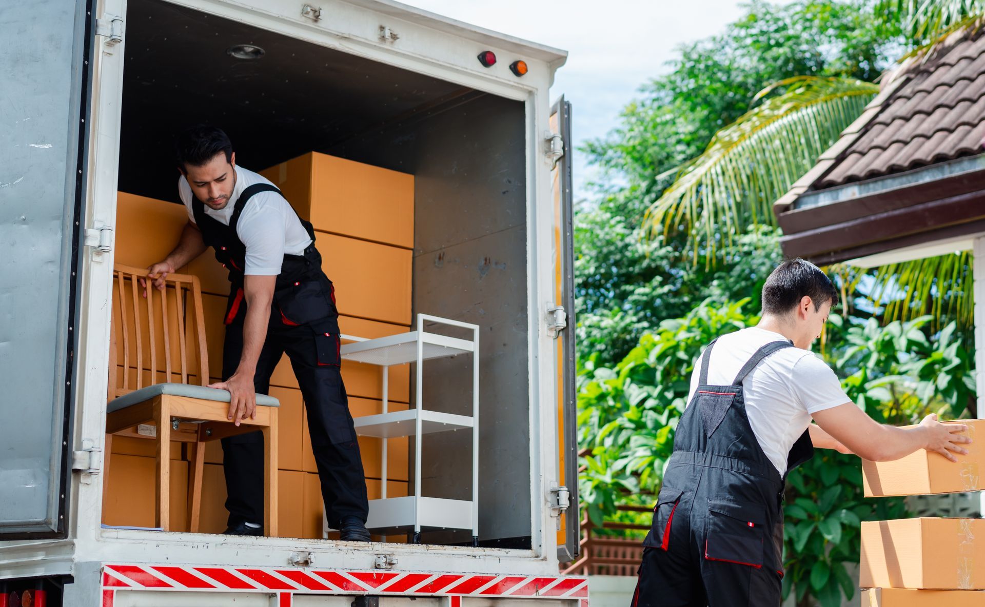 Movers in uniform carrying furniture and labeled boxes up steps. Movers in uniform carrying furniture and labeled boxes up steps.