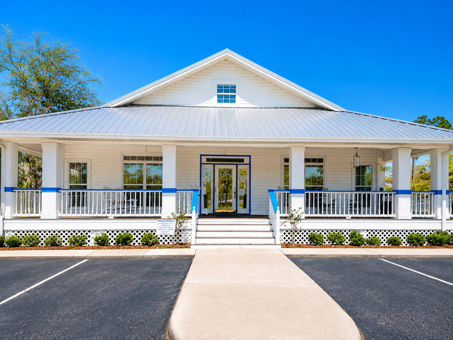 White house with a blue roof, front porch, and central walkway under a clear blue sky