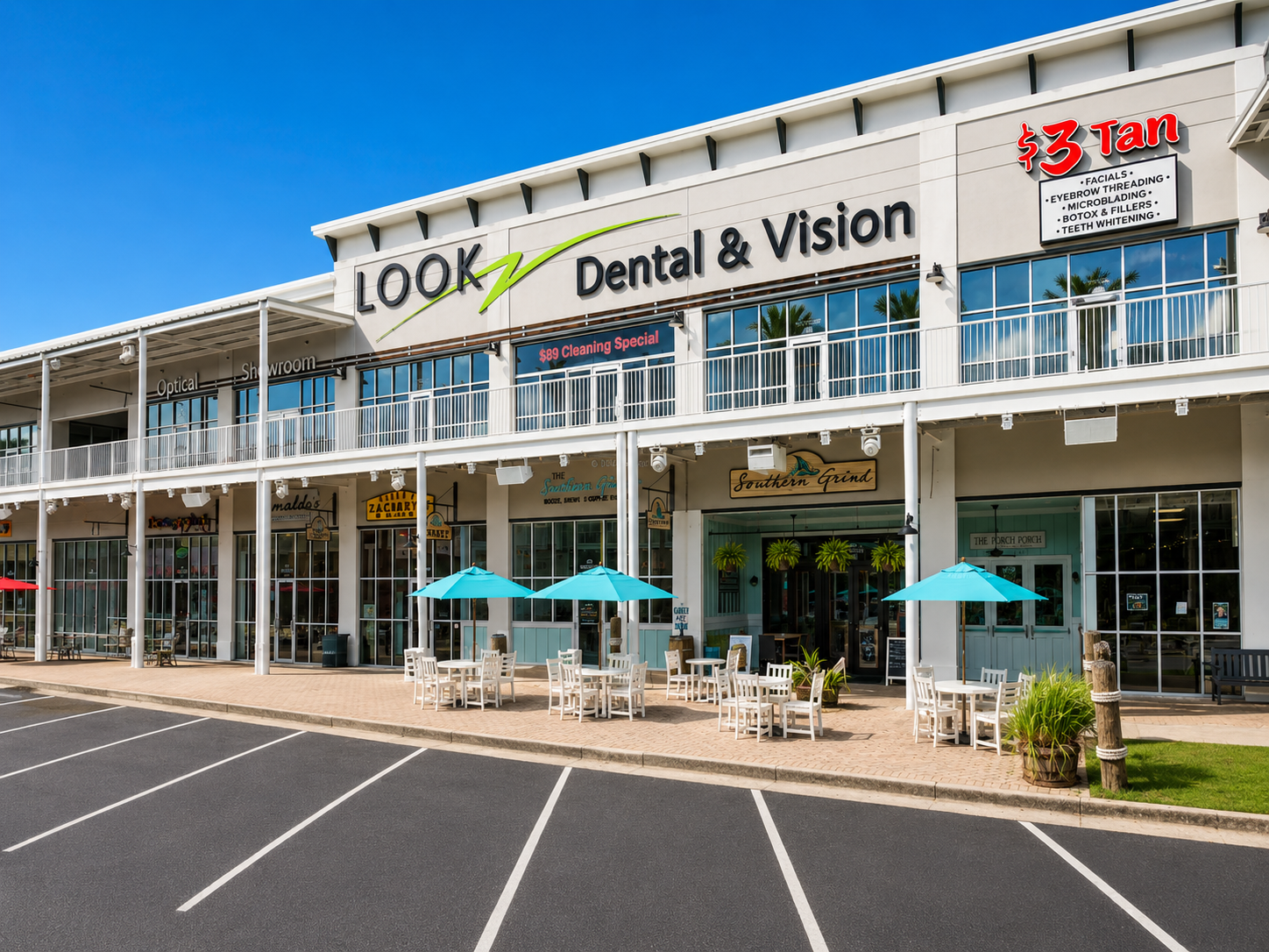 Strip mall storefronts with Dental & Vision and other shops under a clear blue sky