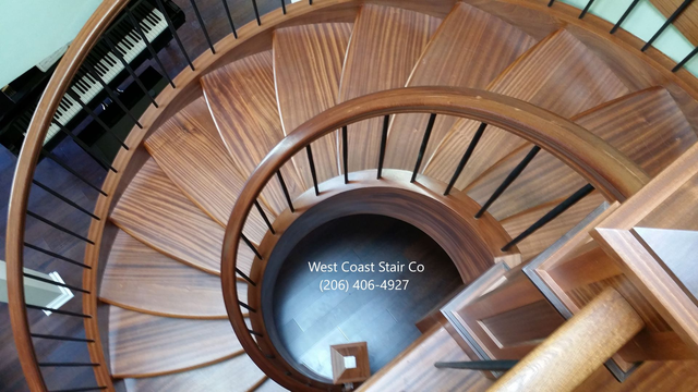 Overhead view of a custom curved wood staircase with a wood handrail and metal balusters