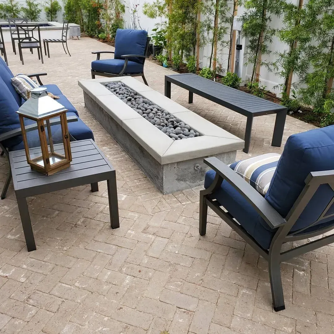 Outdoor patio with blue cushions, fire pit, and brick paving.