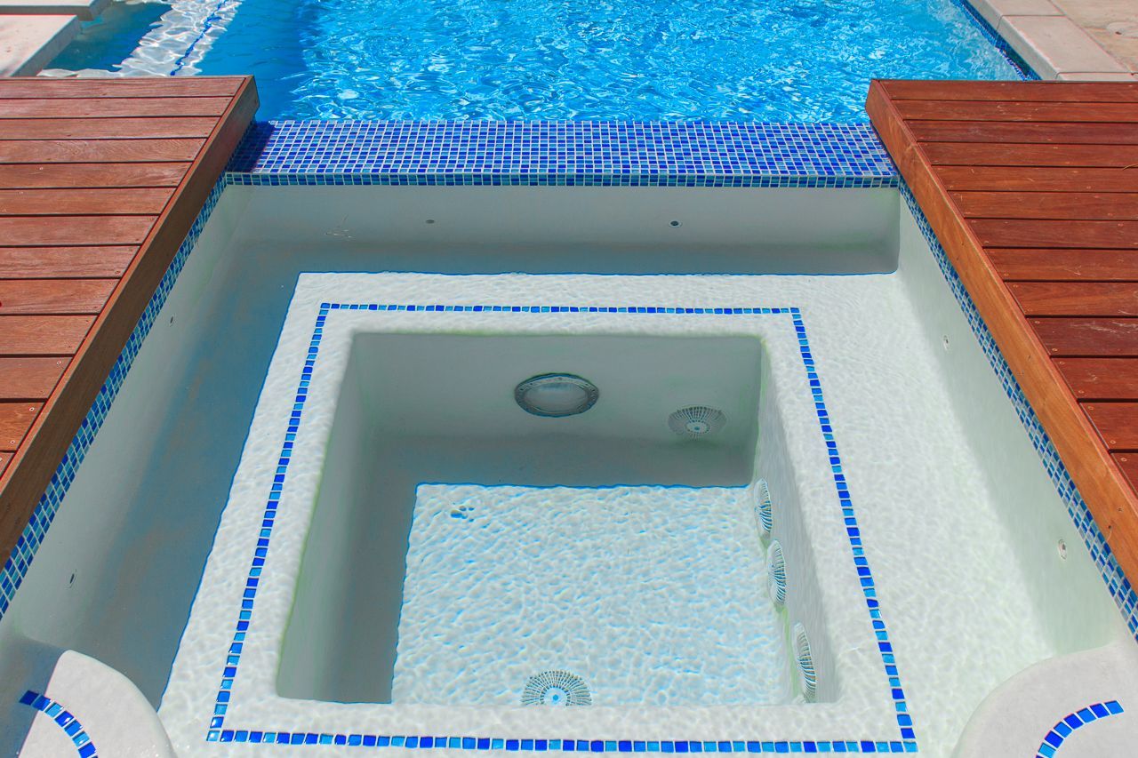 Pool with attached hot tub, blue tile, wooden decking.
