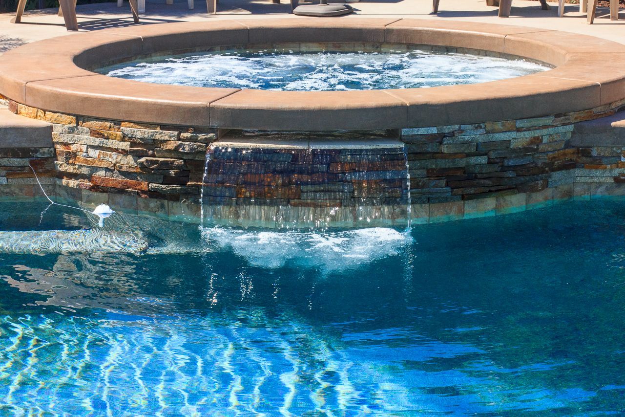 Pool with bubbling water feature cascading into pool; stone and concrete construction.