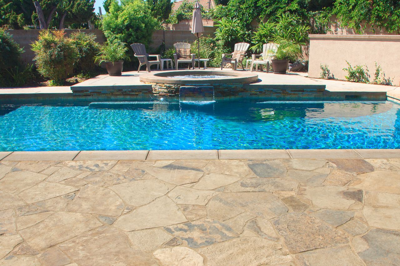 A swimming pool with a stone patio. The water is a bright blue.