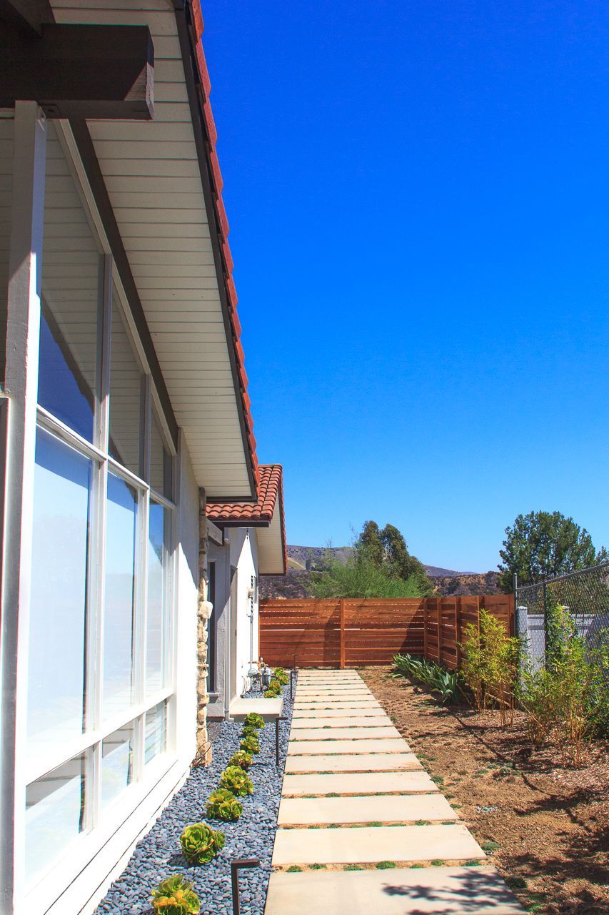Exterior of modern white house with walkway, blue sky.