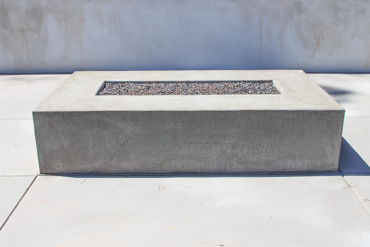 Gray concrete rectangular fire pit on a white tiled patio.
