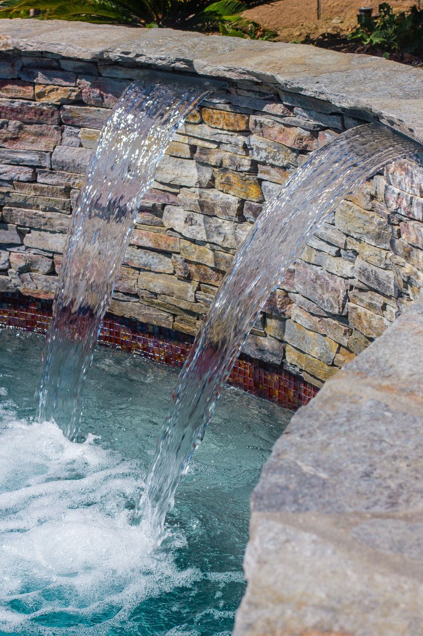 Waterfalls cascading into a pool with stone and brick detail.