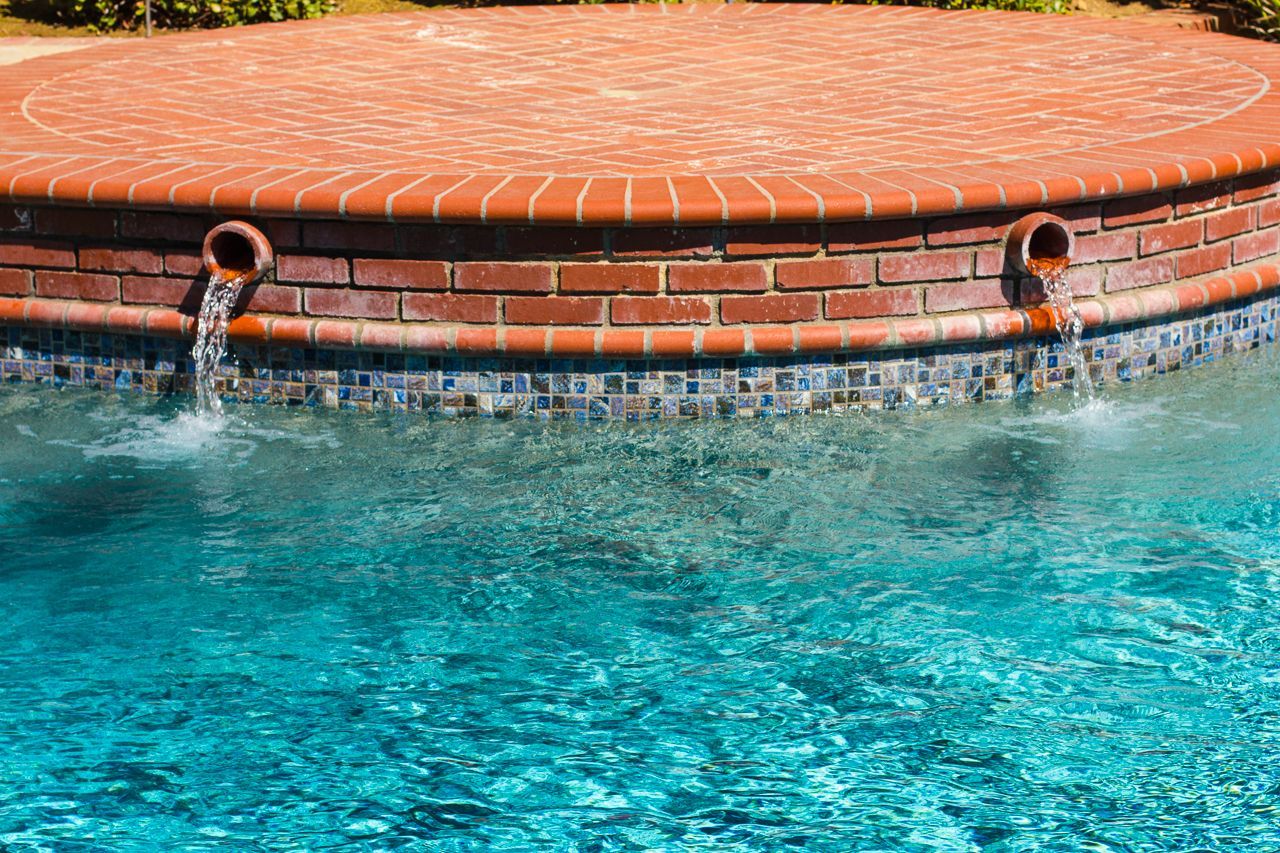 Pool with brick water feature; water flowing from two spouts into blue water.