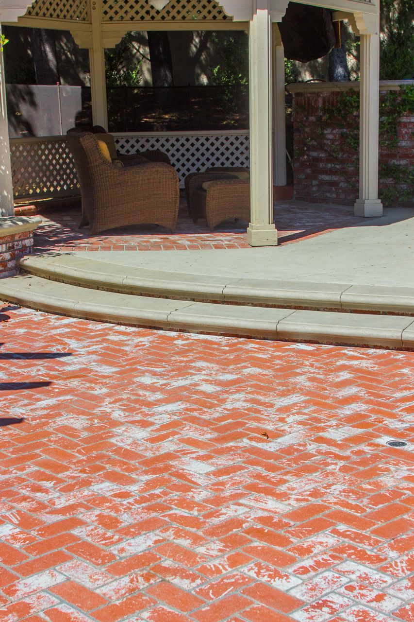 Brick patio leading to a gazebo with seating and a brick accent wall.