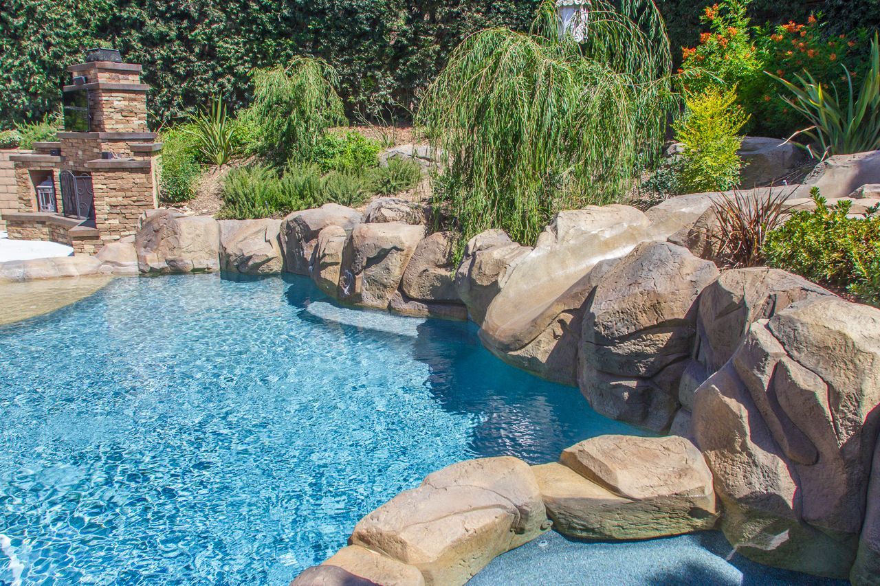 Pool with stone accents and surrounding greenery.