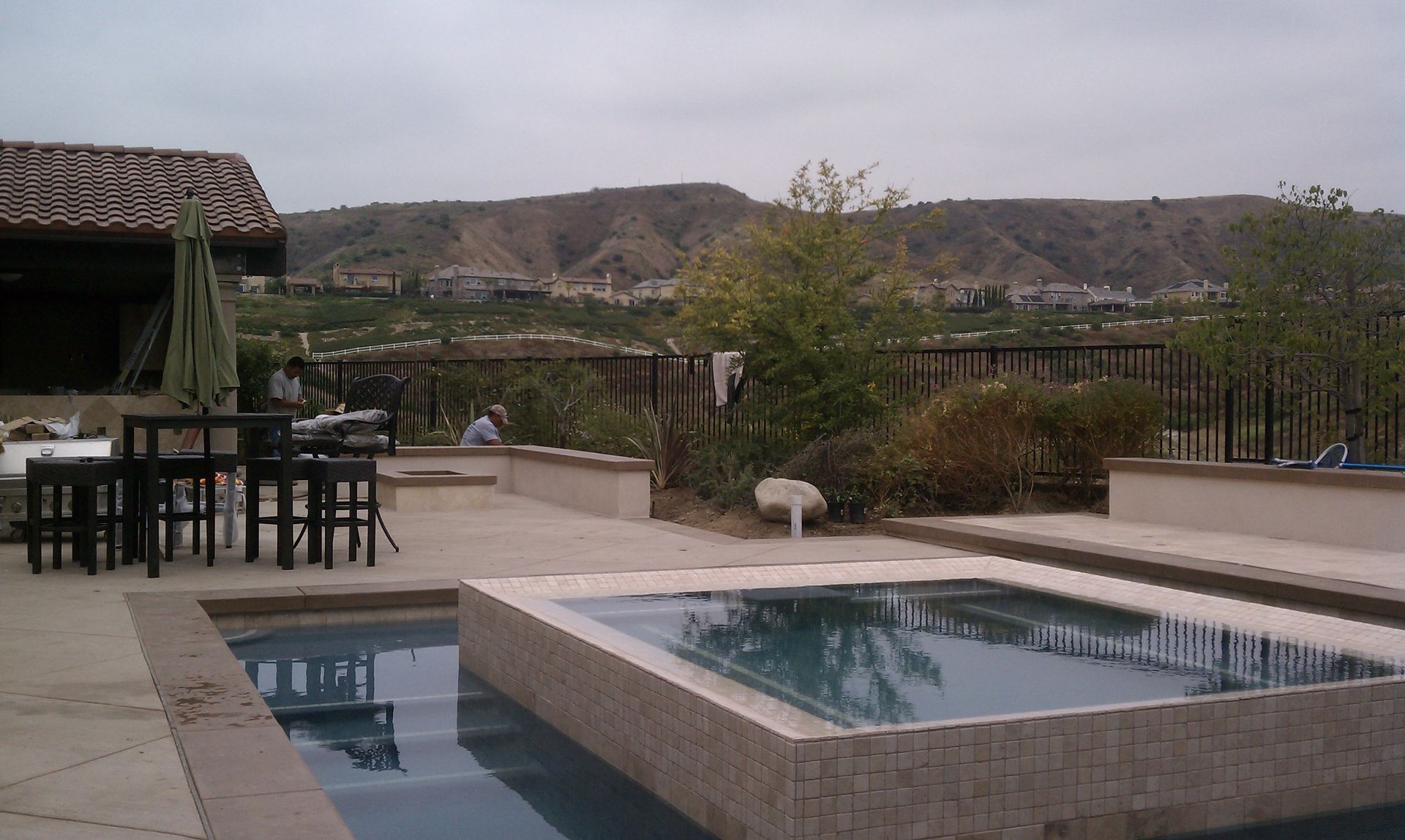 Pool area with mountain view; pools, patio furniture, and a thatched roof.