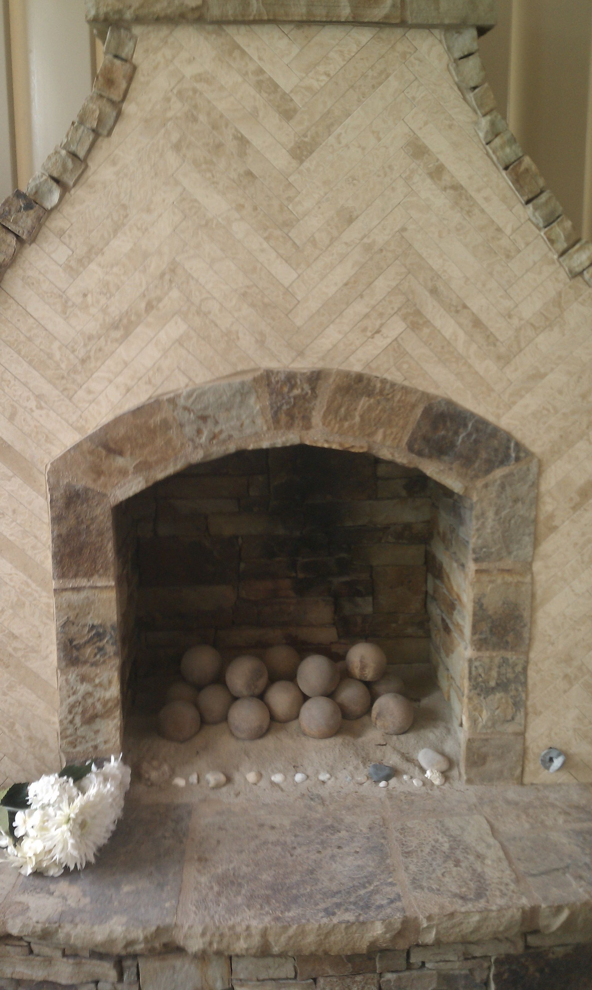 Fireplace with stone facade, herringbone brickwork, arched opening, and decorative balls.