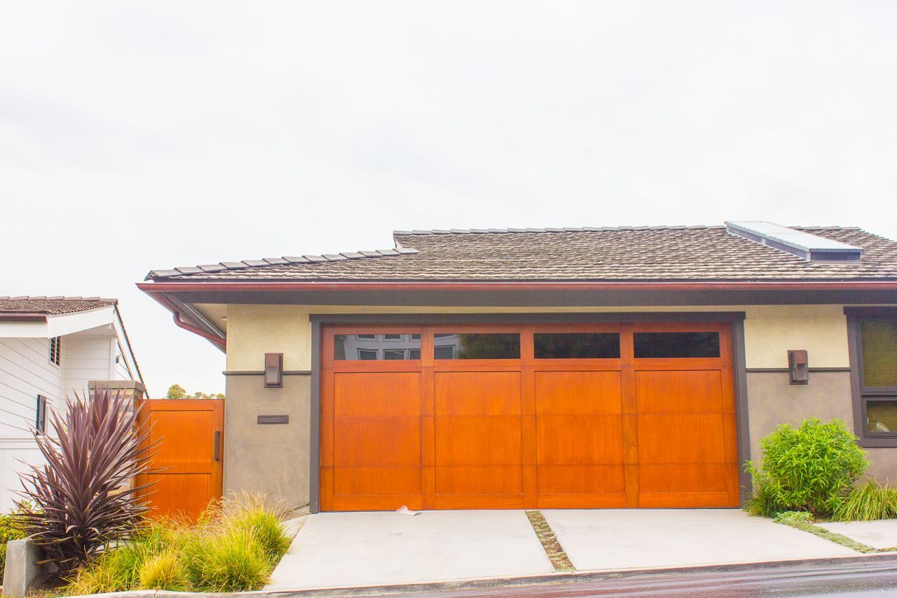 A two-car garage with an orange door and a concrete driveway.