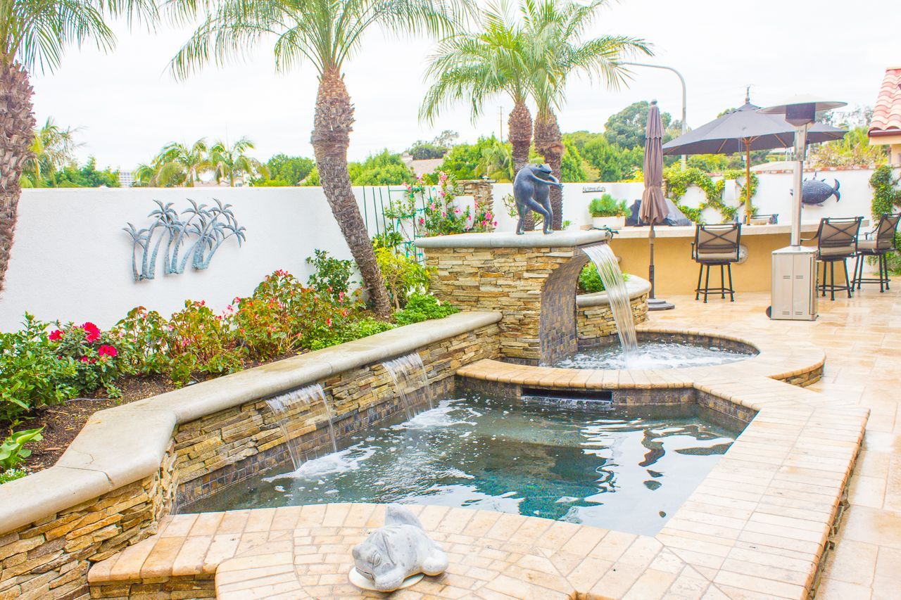 Backyard oasis with a pool, waterfall, and palm trees.