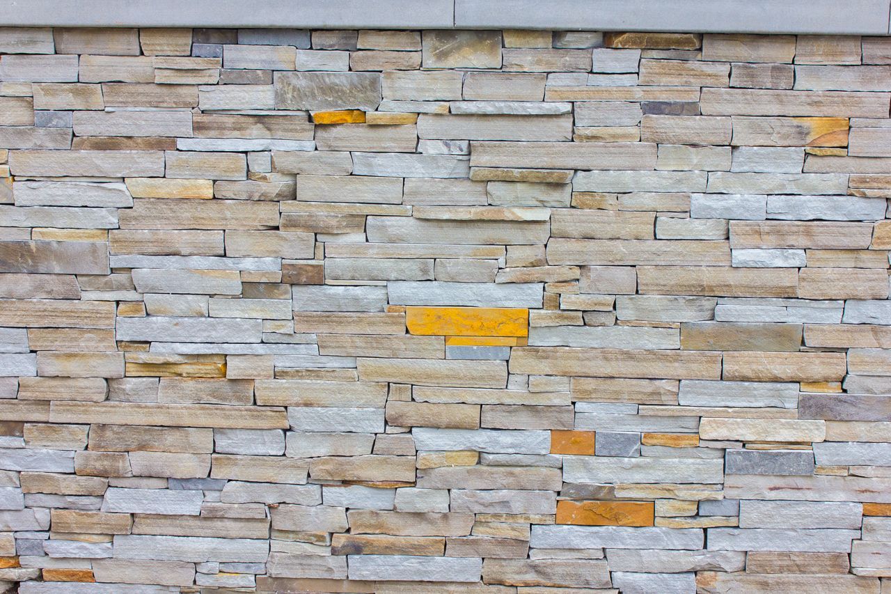 Stone wall with varied shades of gray, beige, and yellow.