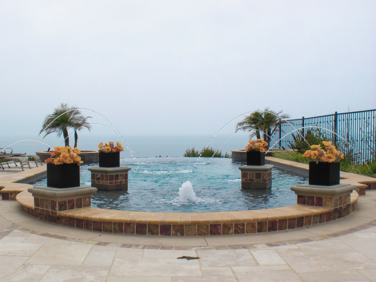 Infinity pool with fountains and flower arrangements; ocean view.