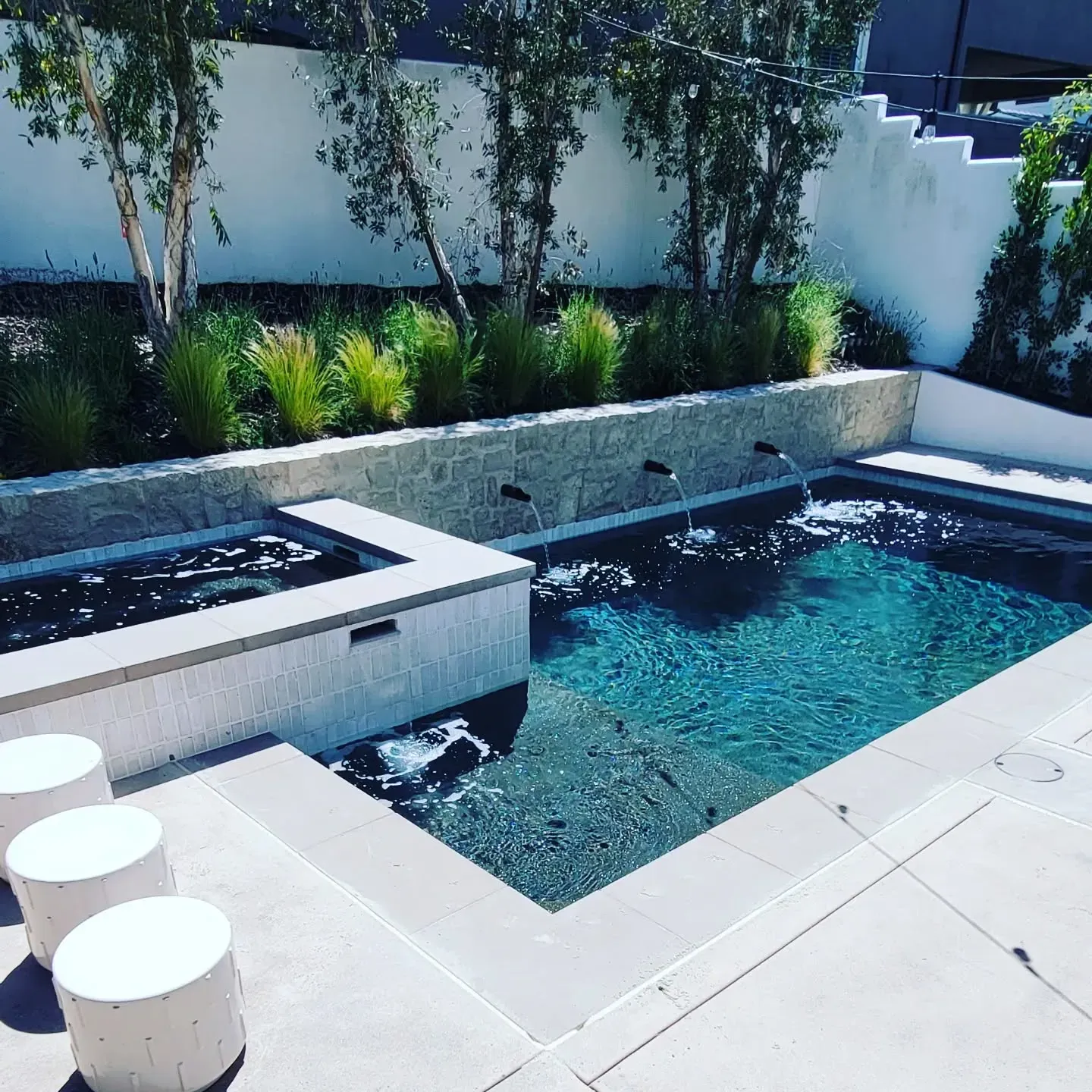 Pool with spa, fountains, and landscaping in a backyard setting.