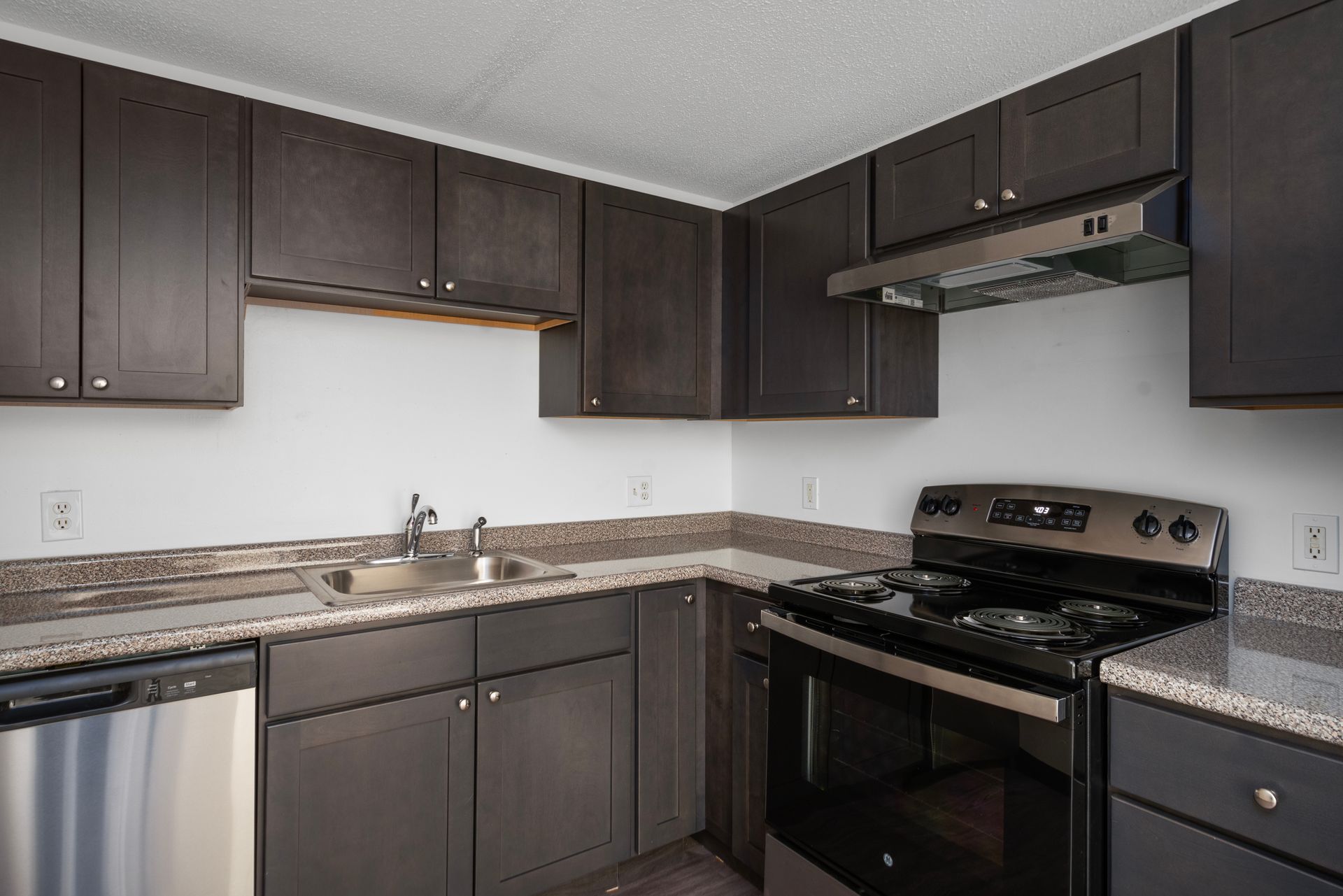 Modern kitchen with dark cabinets, stainless steel appliances, and gray countertops at Penacook Place Apartments in Concord, NH.