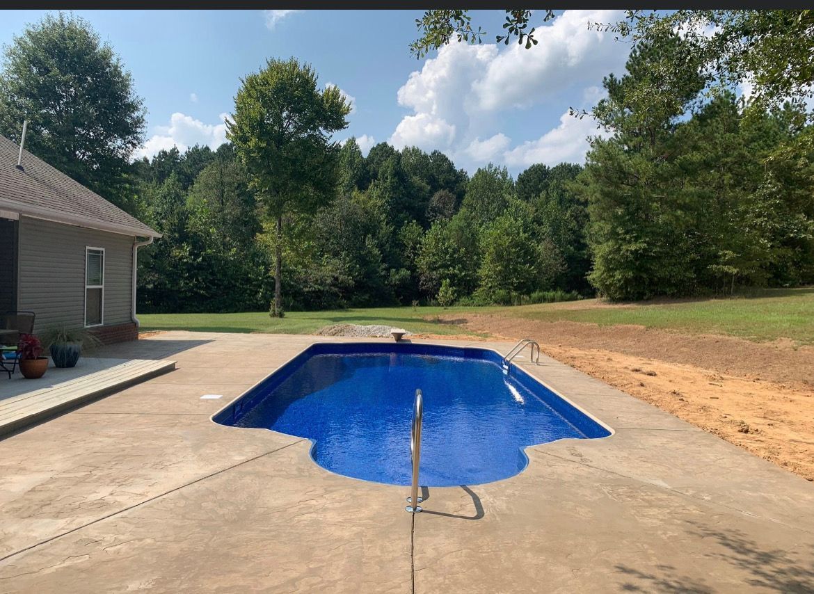 A large blue swimming pool is in the backyard of a house.