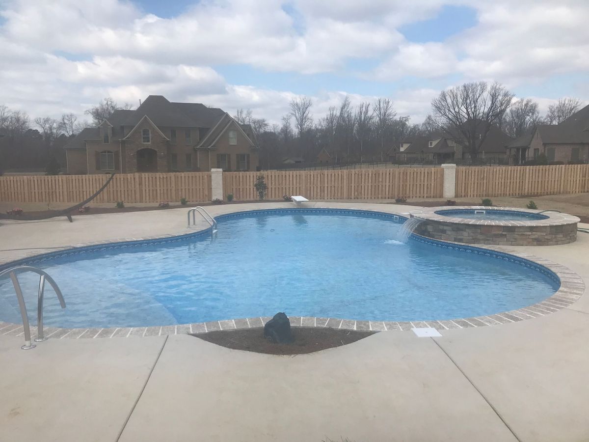 A large swimming pool with a hot tub in the backyard of a house.