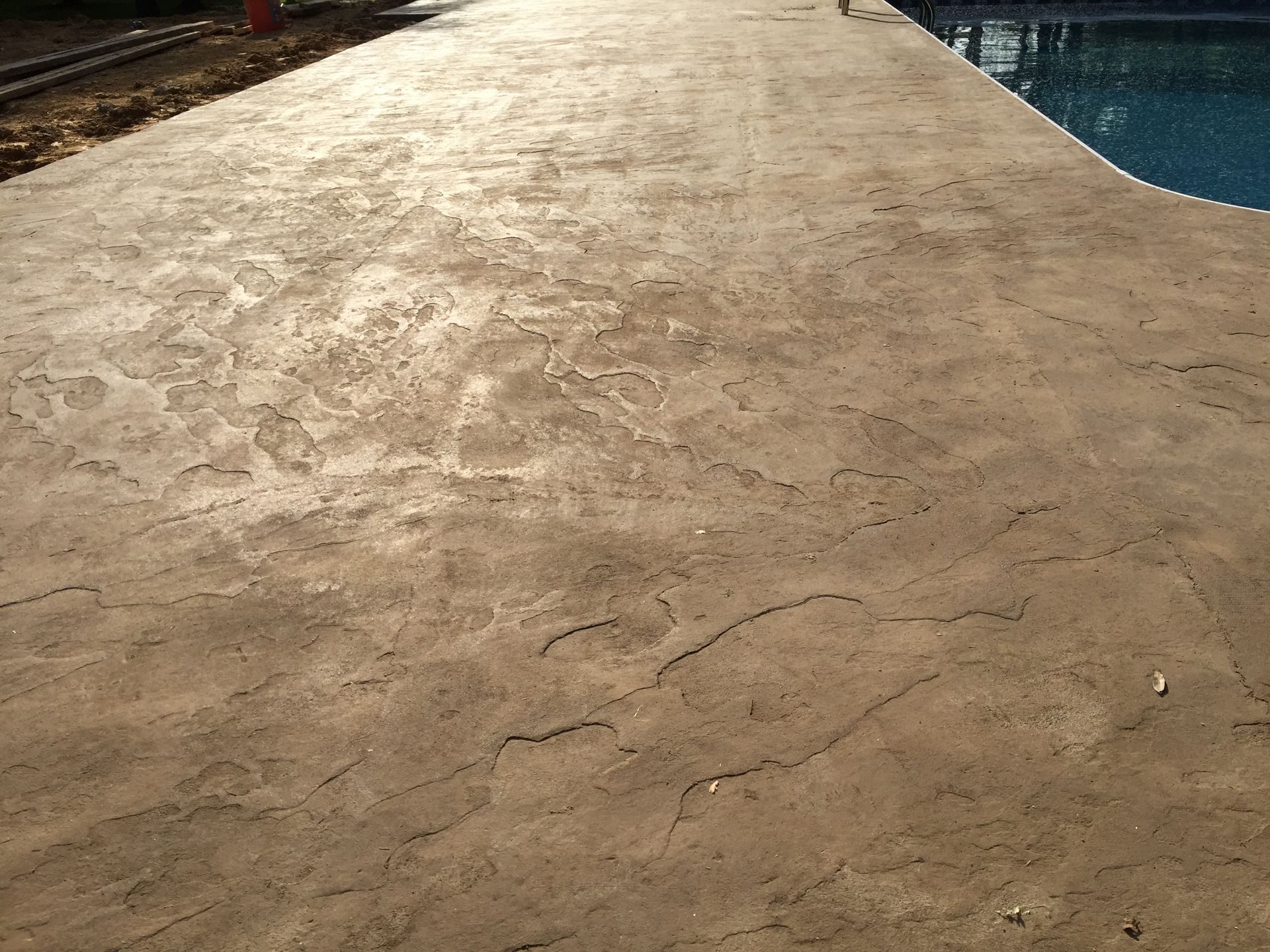 A concrete walkway next to a swimming pool
