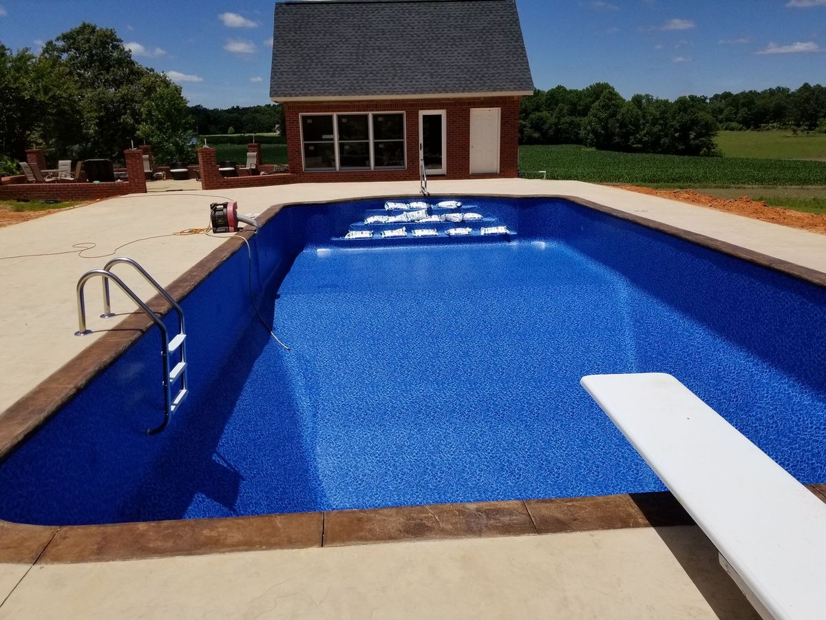 A large swimming pool with a diving board in front of a house