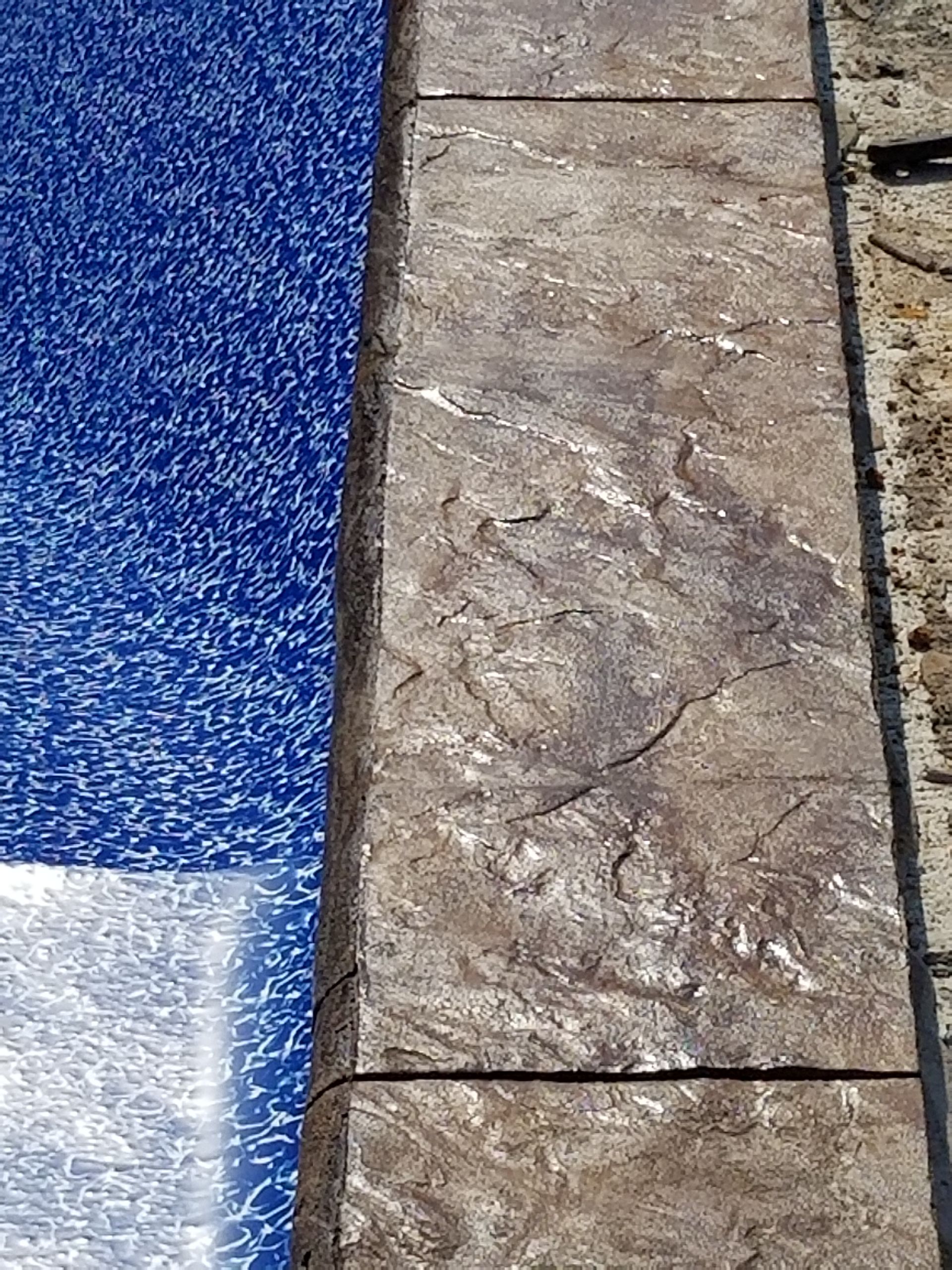 A close up of a tile floor next to a pool.
