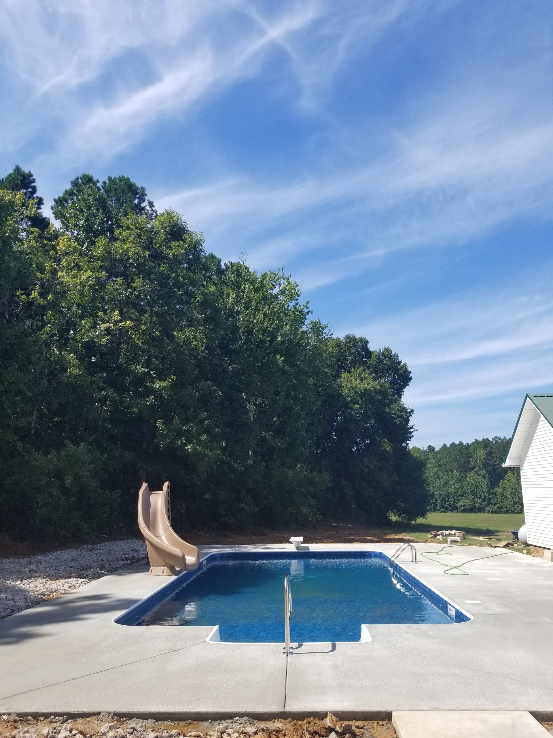 A swimming pool with a slide and trees in the background