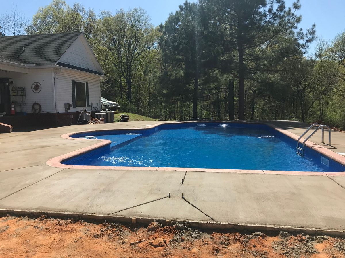 A large swimming pool with a white house in the background