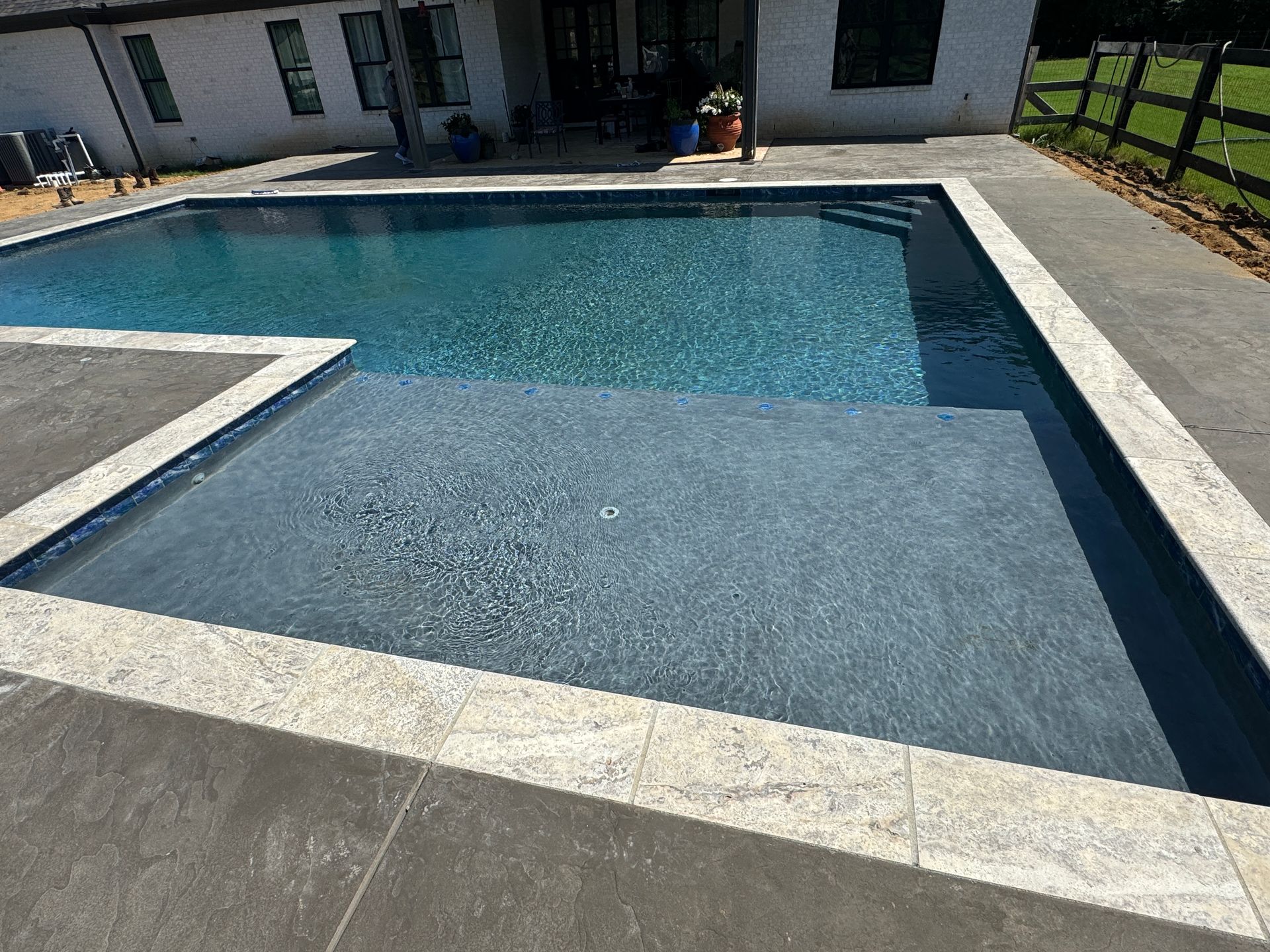 There is a large swimming pool in the backyard of a house.