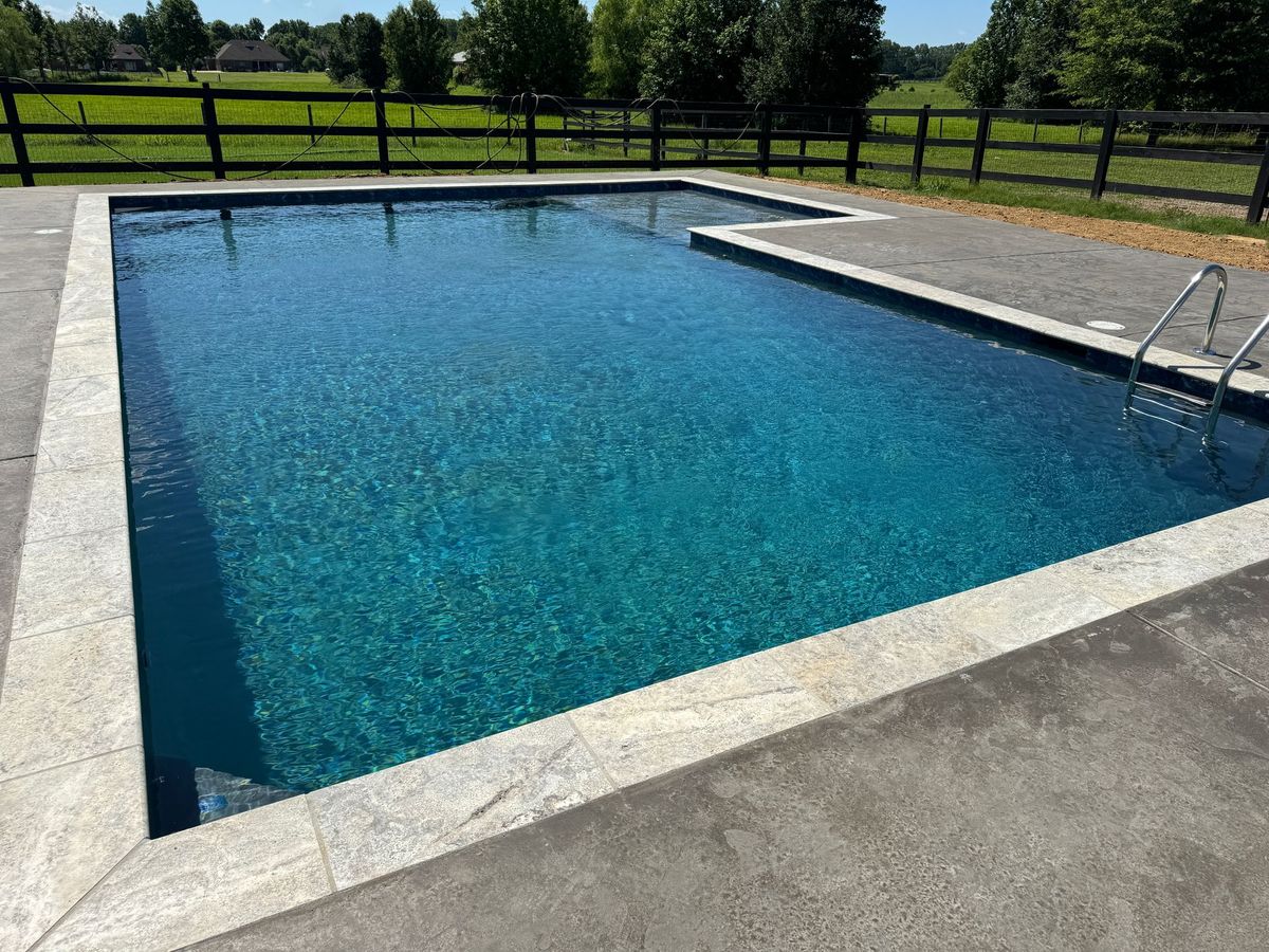 A large swimming pool with a fence in the background.