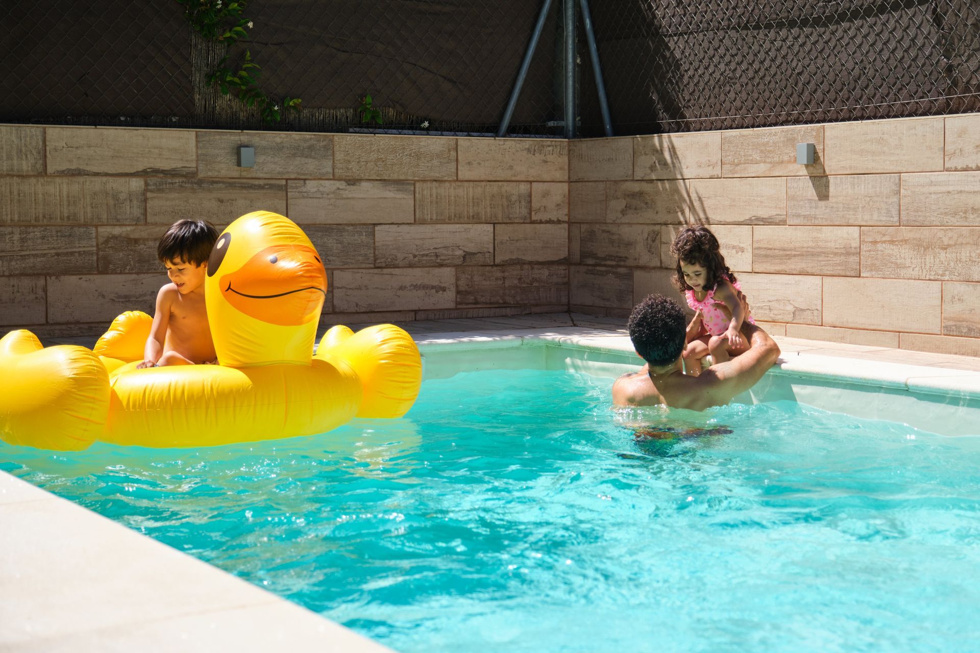 A man is sitting on the side of a swimming pool.