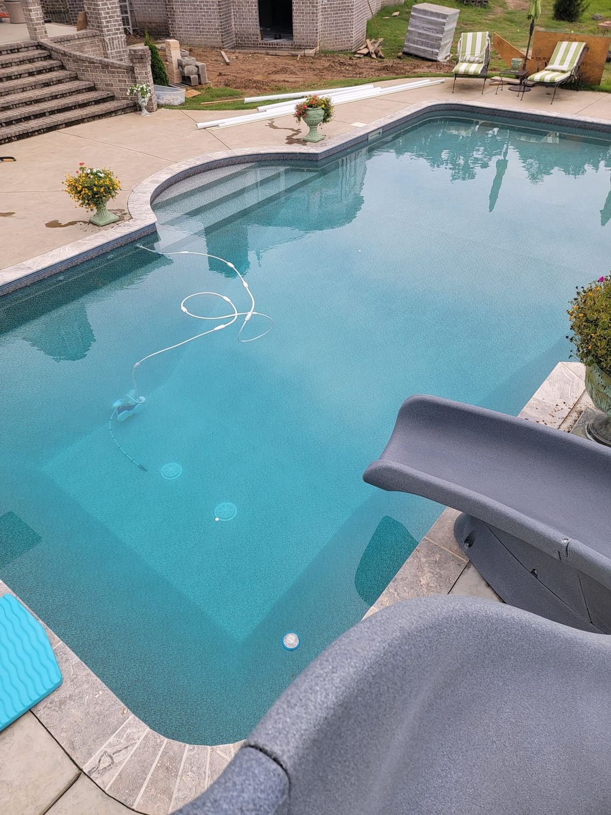 An aerial view of a large swimming pool with two lounge chairs in it.