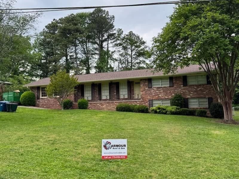 Brick ranch house with a green lawn and a yard sign in front