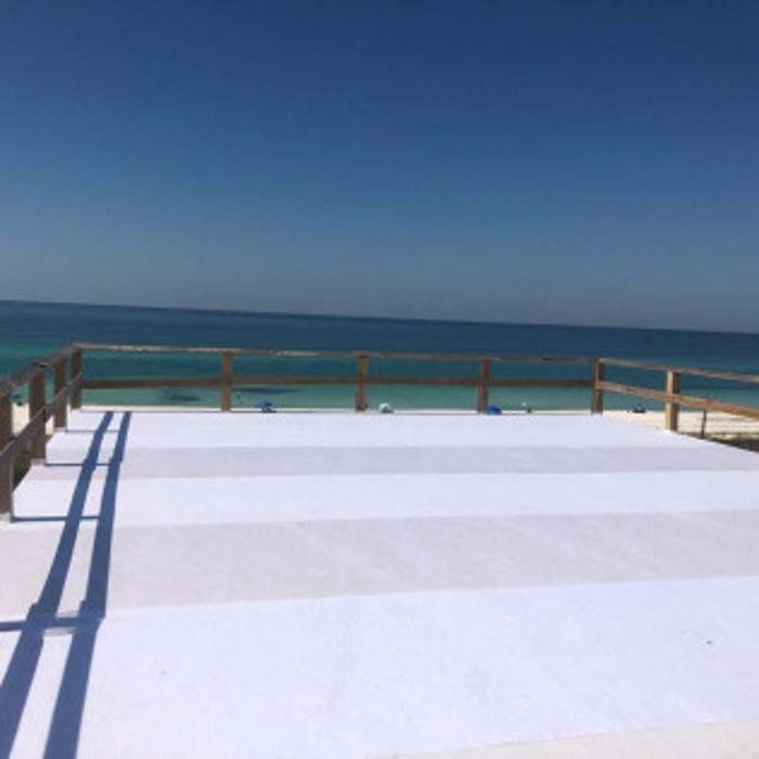 Ocean view from a bright white deck with wooden railing under a clear blue sky