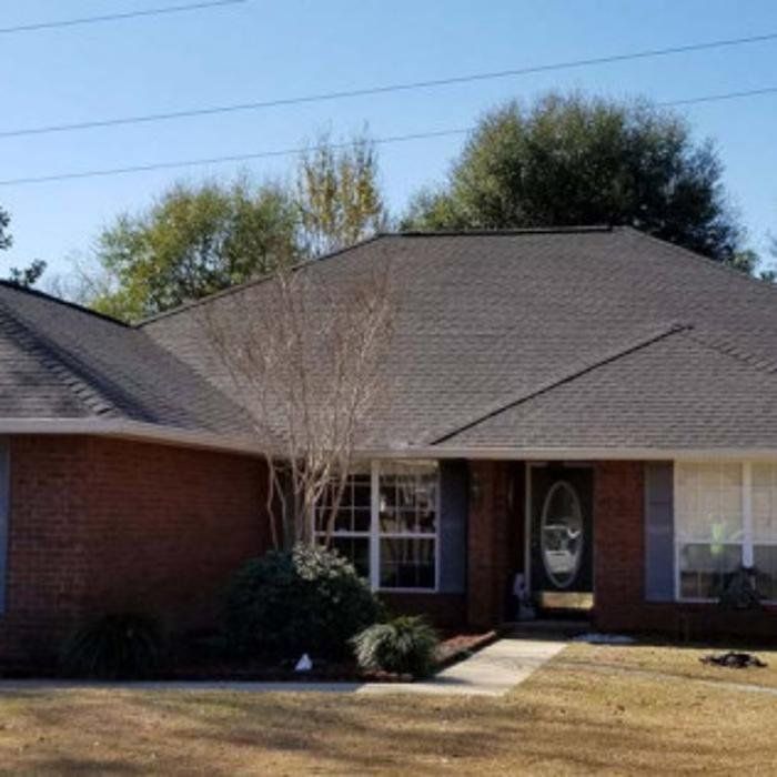 Single-story brick house with a gray roof, front lawn, and walkway to the front door