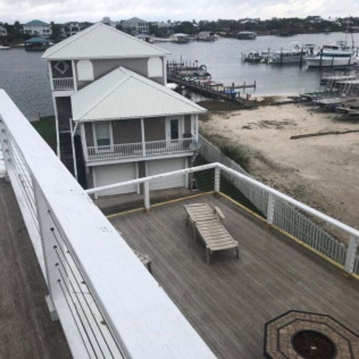 Waterfront deck overlooking sandy shore, houses, docks, and boats on a gray day