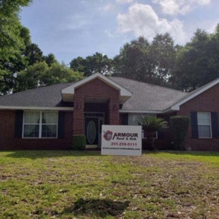 Brick house with a front lawn and a sign reading “ARMOUR Pest & Deck” by the entrance