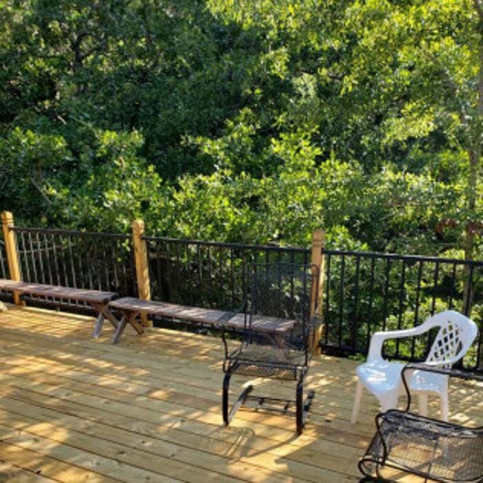 Wooden deck with benches and white chair overlooking dense green trees