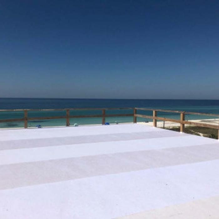 White rooftop deck overlooking a calm blue ocean under a clear sky